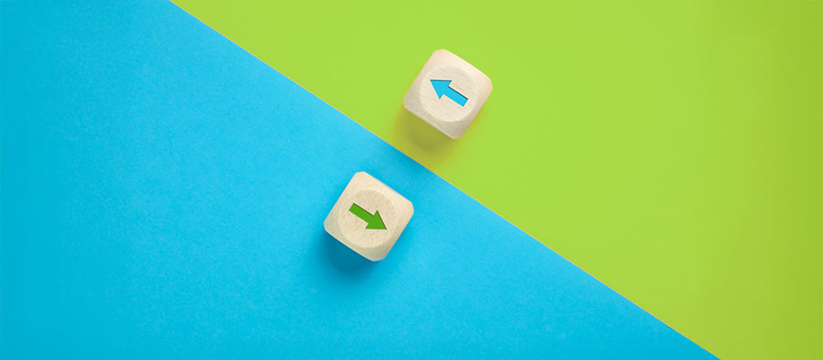 Arrow icons in contrast on wooden cubes moving towards opposite directions