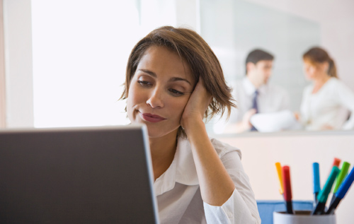 A female-presenting person in business casual clothing working with a laptop in an office.