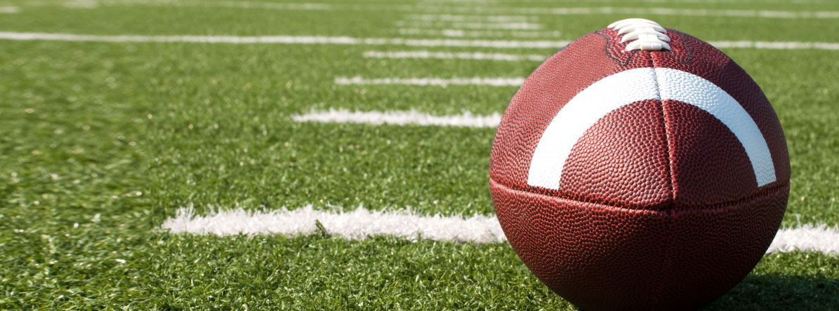 An American football sits on a football field.